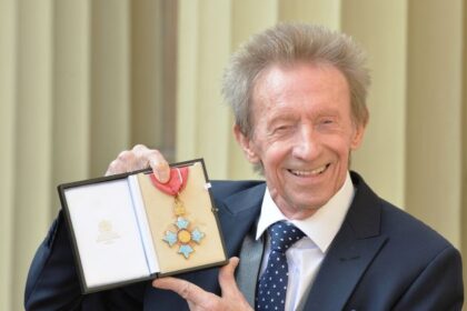 Former Scotland and Manchester United footballer Denis Law poses with his CBE.