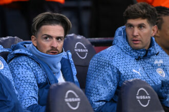 Manchester City substitutes Jack Grealish and John Stones (r) look on from the bench during the Emirates FA Cup Quarter Final match between Manchester City and Newcastle United at Etihad Stadium on March 16, 2024 in Manchester, England.