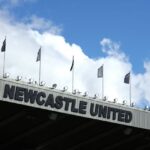 Blue sky appears above the Newcastle United sign