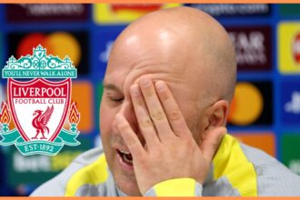 Liverpool head coach Arne Slot rubs his face with one hand.