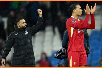 Mo Salah holds his fist in the air as Virgil van Dijk claps Liverpool fans.