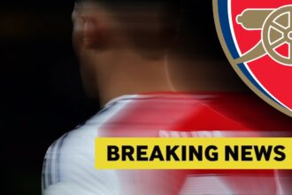 Blurry close up of William Saliba in action for Arsenal, plus yellow breaking news banner