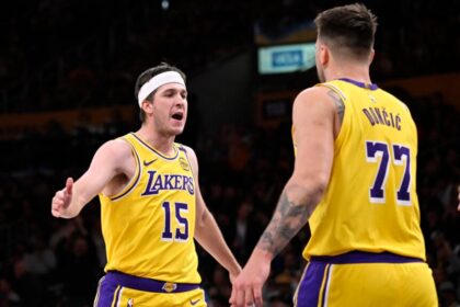 Austin Reaves #15 of the Los Angeles Lakers high fives teammate Luka Doncic #77 of the Los Angeles Lakers after a three point basket against the Denver Nuggets in the first half of a NBA basketball game at Crypto.com Arena.