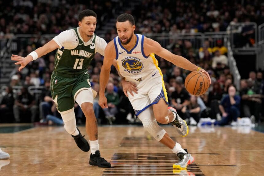 Stephen Curry #30 of the Golden State Warriors dribbles the ball against Ryan Rollins #13 of the Milwaukee Bucks during the second quarter at Fiserv Forum.