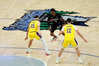 Jaden McDaniels #3 of the Minnesota Timberwolves dribbles the ball against Austin Reaves #15 and Jake LaRavia #12 of the Los Angeles Lakers in the first quarter at Target Center on October 29, 2025 in Minneapolis, Minnesota.