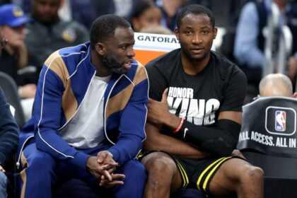 Draymond Green #23 (left) speaks to Jonathan Kuminga #00 of the Golden State Warriors on the bench during their game against the New Orleans Pelicans.