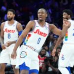 Tyrese Maxey #0, Paul George #8, and Joel Embiid #21 of the Philadelphia 76ers look on against the Toronto Raptors at the Wells Fargo Center.