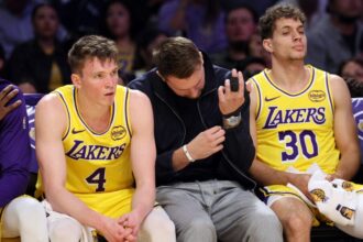 Luka Doncic #77 of the Los Angeles Lakers, with his finger wrapped, is seated between Dalton Knecht #4 and Chris Manon #30 during the second half of the game against the Portland Trail Blazers at Crypto.com Arena.