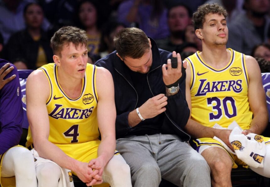 Luka Doncic #77 of the Los Angeles Lakers, with his finger wrapped, is seated between Dalton Knecht #4 and Chris Manon #30 during the second half of the game against the Portland Trail Blazers at Crypto.com Arena.